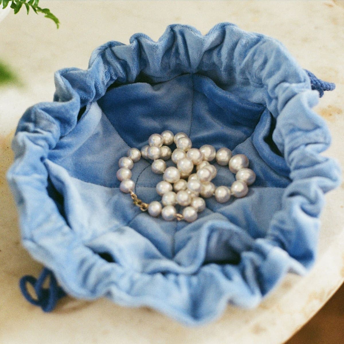 A pearl necklace resting in a soft fabric pouch